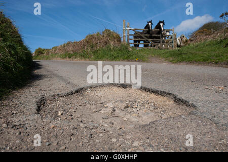 Countryside potholes in the road cause damage to cars and are a danger to unsuspecting motorcyclists and cyclists pot hole Stock Photo