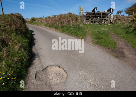 Countryside potholes in the road cause damage to cars and are a danger to unsuspecting motorcyclists and cyclists pot hole Stock Photo