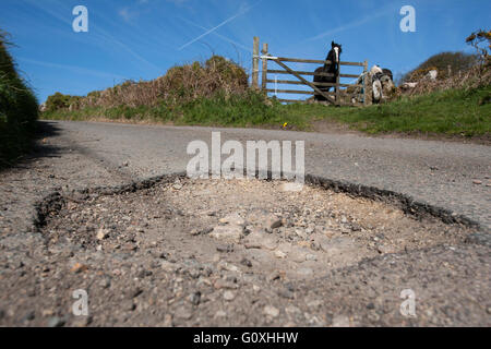 Countryside potholes in the road cause damage to cars and are a danger to unsuspecting motorcyclists and cyclists pot hole Stock Photo