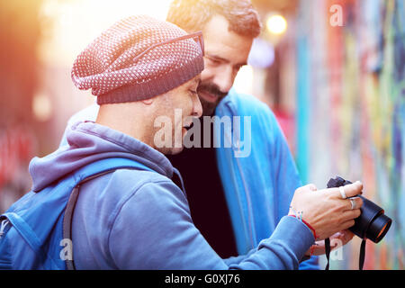 Two happy friends outdoors, conversing and looking at the images on the photo camera, best friends enjoying active summer Stock Photo