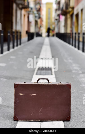 closeup of an old brown suitcase in the middle of a street Stock Photo