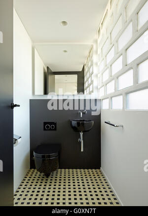Escorial Apartment, Barcelona, Spain. A small black toilet and handbasin in a room with tiled floor and walls. Stock Photo