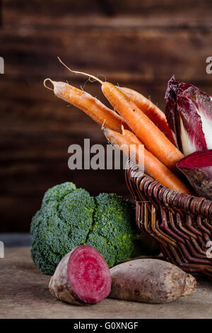 Basket full of healthy vegetables like carrots, beetroot, chicory, broccoli in wooden background Stock Photo