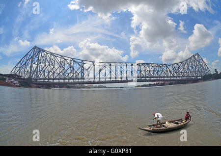 Fishermen with fishing boat on Hooghly river with Howrah Bridge at background, Kolkata, West Bengal, India Stock Photo