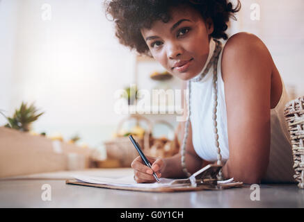 Portrait of beautiful young african woman working in a juice bar. Female standing behind the counter and writing notes. Stock Photo