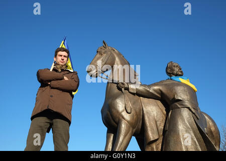 Kryvyi Rih, Ukraine - December 13, 2015: Man with Ukrainian flag standing near monument to Kryvyi Rih city founder Cossack Rih Stock Photo