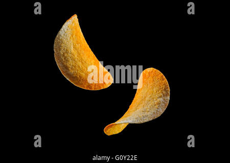 Falling potato saddle-form chips isolated on black background Stock Photo