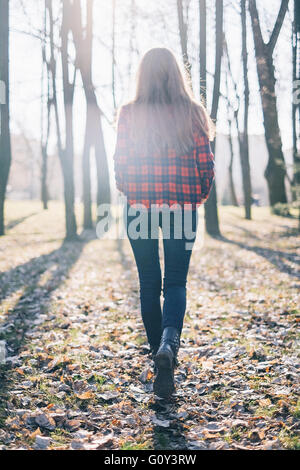 Rear view of hipster woman walking through woodland Stock Photo