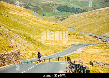 Female cyclist descending Buttertubs Pass above Swaledale in the Yorkshire Dales Stock Photo