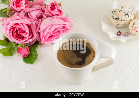 Pink roses and a coffee cup on white silk textile Stock Photo