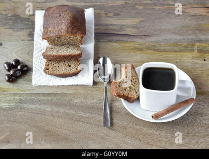 White square cup of coffee and brown, gluten free cake set on wooden table and decorated with cinnamon stick and chocolate cover Stock Photo