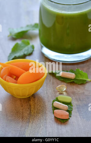 Green detox smoothie and dietary supplements and a serving of apricots on wooden table Stock Photo