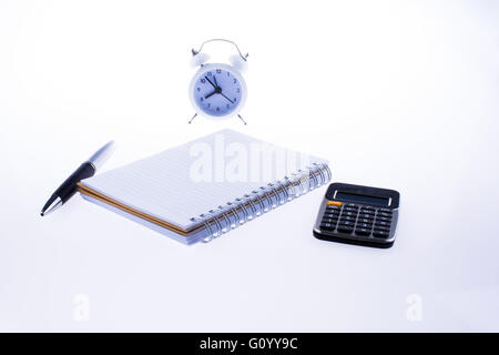 Notebook, alarm clock, calculator and pen on white background Stock Photo