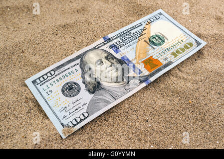 Hundred US dollars banknote in hot desert sand Stock Photo
