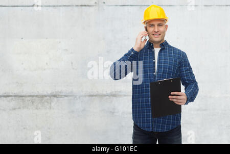smiling builder in helmet calling on smartphone Stock Photo