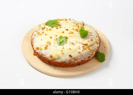 homemade gingerbread cake with cream cheese topping and chopped walnuts on wooden cutting board Stock Photo