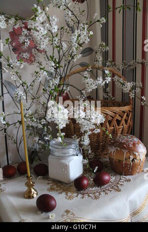 prepare celebration traditional Christian Easter cake, salt, painted red eggs, candle with cherry bloom bouquet Stock Photo