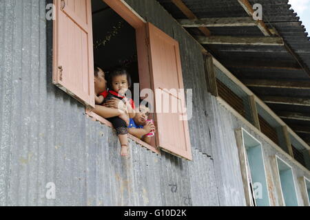 Longhouse village in Sarawak Malaysia. Father and children of Sarawak native looks out from the Longhouse wooden window. Stock Photo