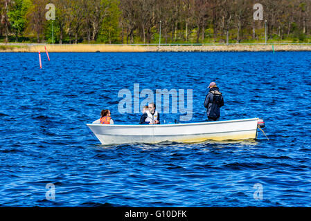 Karlskrona, Sweden - May 03, 2016: Four persons in a small open motorboat fishing at sea with coastline in background. Boat is m Stock Photo