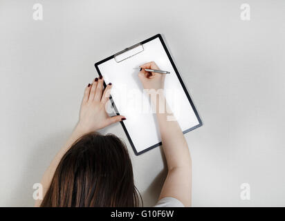 Clipboard with blank paper in female hands. Stock Photo