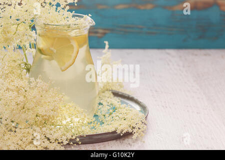 Elderflower juice with lemon in a glass jug. Elderflower lemonade with a slice of lemon and elderflower on a wooden table Stock Photo