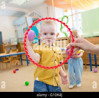 Happy kid playing with ball and ring in kindergarten Stock Photo