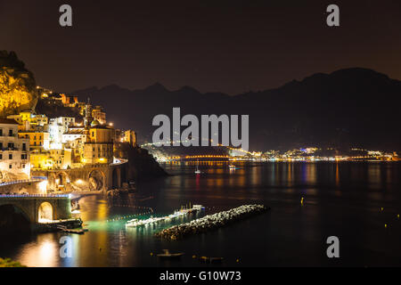 Night view of Amalfi on coast line of mediterranean sea, Italy, with colorful lights from the town and the dock, and the silhoue Stock Photo