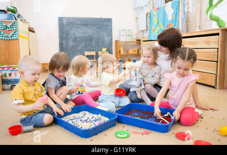 Children with teacher improving hands motor skills in kindergarten Stock Photo