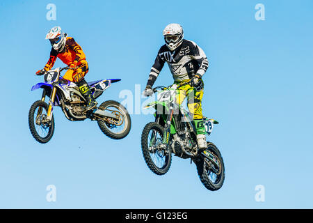 closeup of two motorcyclists jump from a mountain on background of blue sky during Cup of Urals Stock Photo