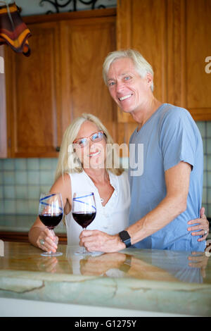 Senior couple enjoying retirement in their kitchen while having red wine Stock Photo