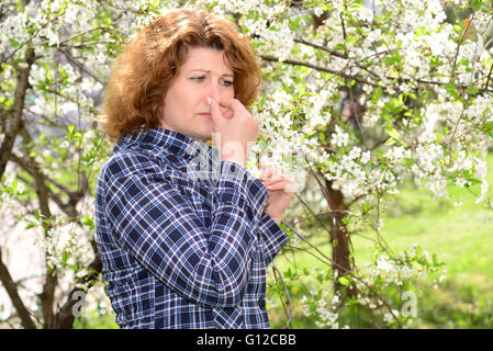 Woman suffering from allergic rhinitis in lush park Stock Photo