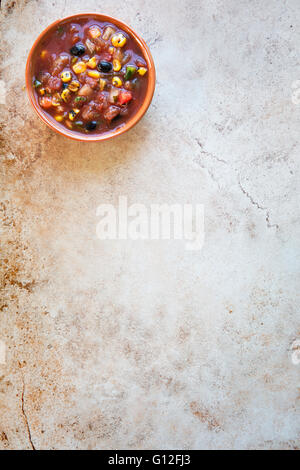 Bowl of fresh salsa on stone surface with copy space and viewed from above. Stock Photo