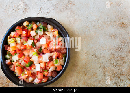 Bowl of fresh pico de gallo on stone surface with copy space and viewed from above. Stock Photo