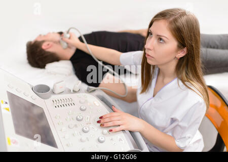 Man being checked for thyroid at ultrasound device in a hospital Stock Photo