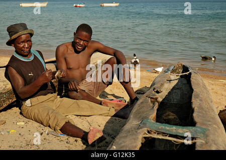 Two men sitting on the beach on the shore of Lake Malawi in Chembe village, Cape Maclear Stock Photo