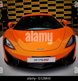 Orange McLaren 570S Spider modern supercar in a display box at a square