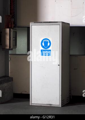 Metal cupboard with blue sign saying Ear Protection Must Be Worn In This Area Stock Photo