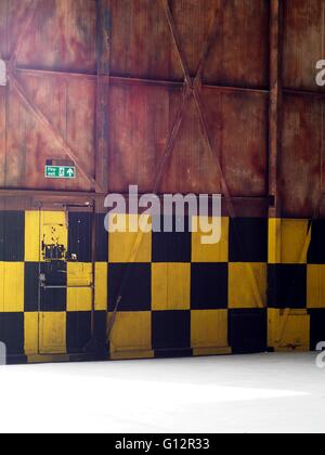 Aircraft Hangar door with Fire Exit sign above fire exit door Stock Photo