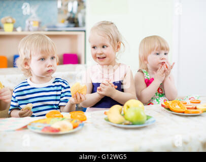 kids eating fruits in kindergarten dinning room Stock Photo