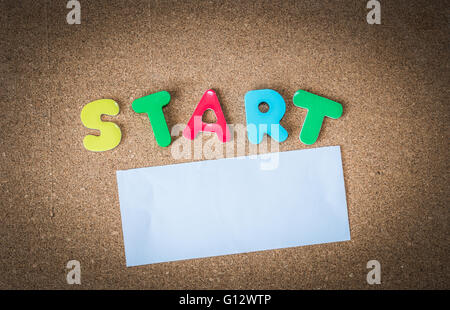 Colorful Wooden word START with white paper on cork board Stock Photo