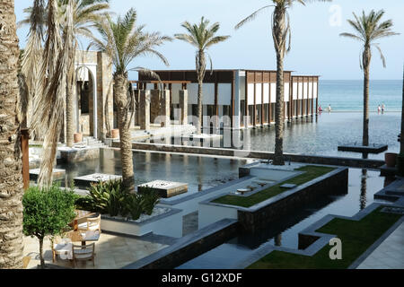 HERAKLION, CRETE, GREECE - MAY 13, 2014: The big blue swimming-pool, modern building with columns, palms and beach in hotel Stock Photo