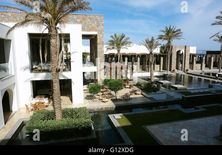 HERAKLION, CRETE, GREECE - MAY 13, 2014: The blue sky, swimming-pool, modern building with columns and palms in luxury hotel Stock Photo