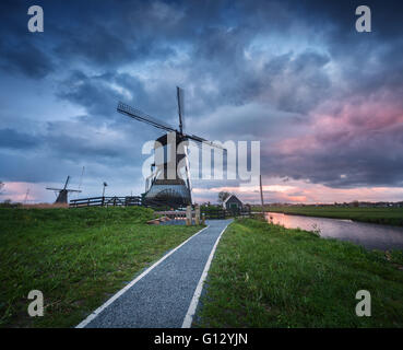 Beautiful landscape with traditional dutch windmills near the famous water canals with dramatic sky, colorful clouds and trail Stock Photo
