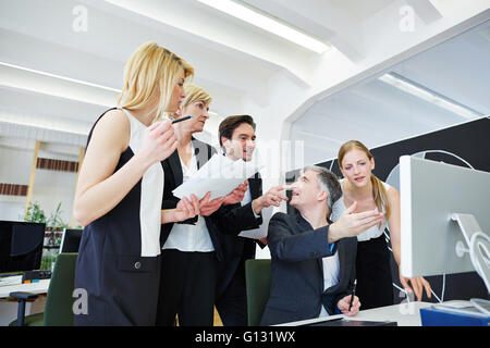Business team in office looking at broken computer on desk Stock Photo