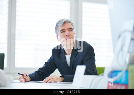 Pensive business man sitting at desk in the office Stock Photo