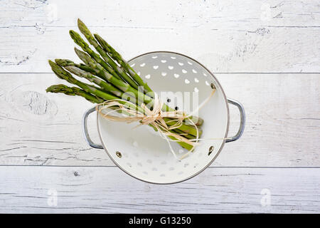 Fresh green asparagus in colander on old wooden background Stock Photo