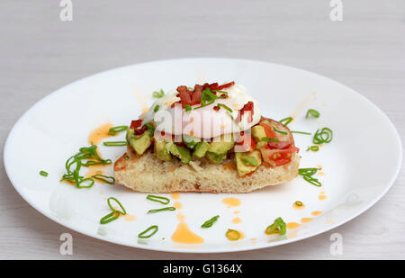 Poached eggs bacon tomatoes and avocado on toast Stock Photo
