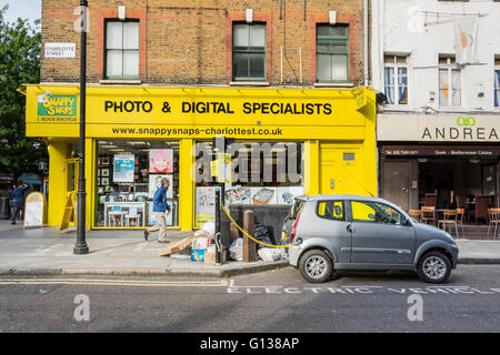 Electric car recharging in front of Snappy Snaps on Charlotte Street, London, UK. Stock Photo