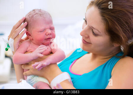 Mother giving birth to a baby. Newborn baby in delivery room. Mom holding her new born child after labor. Stock Photo