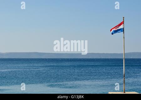 Croatian national flag flying at windy day with adriatic sea in background Stock Photo